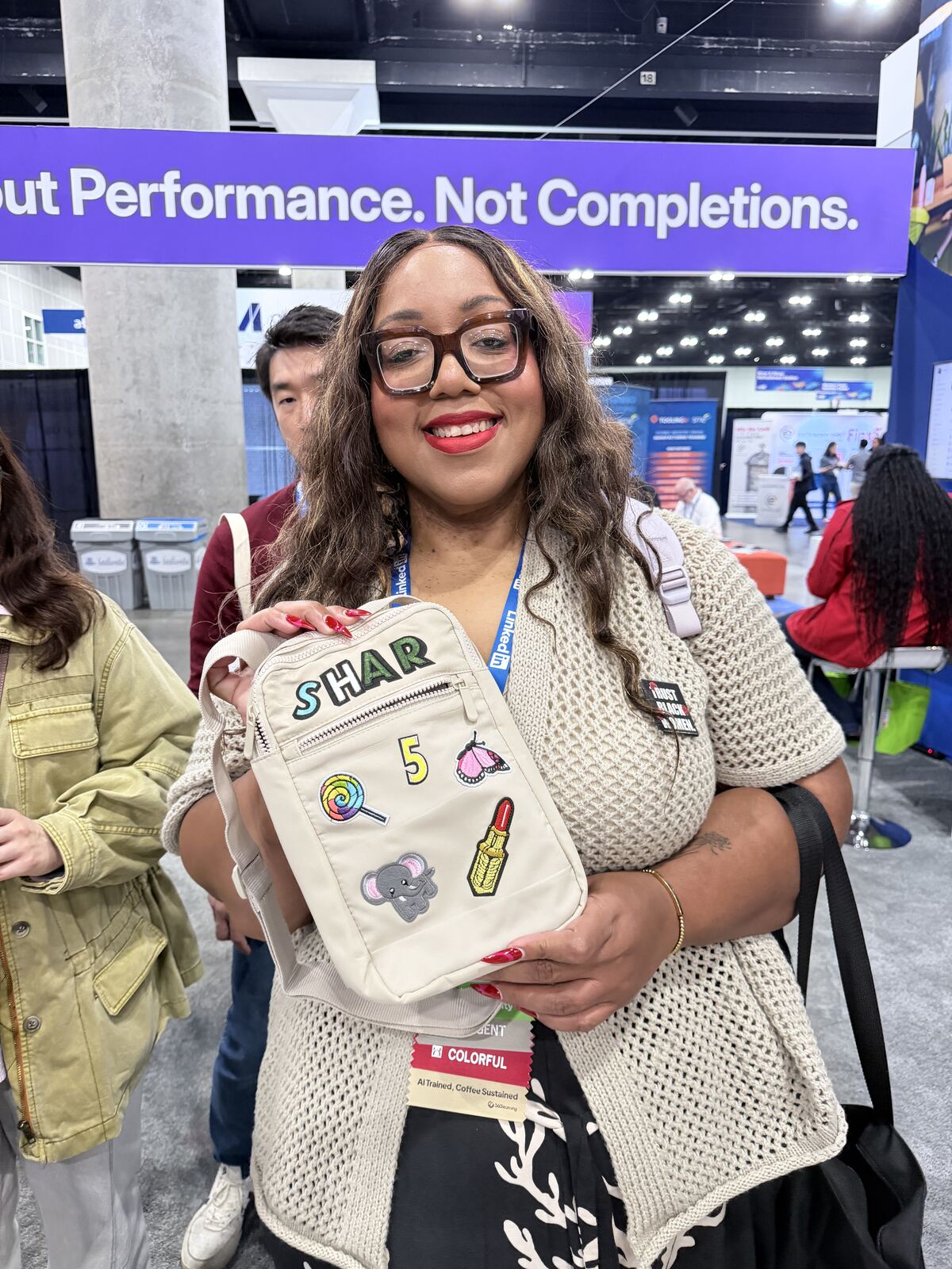 Person holding a custom tote bag with patches and stickers at a booth event